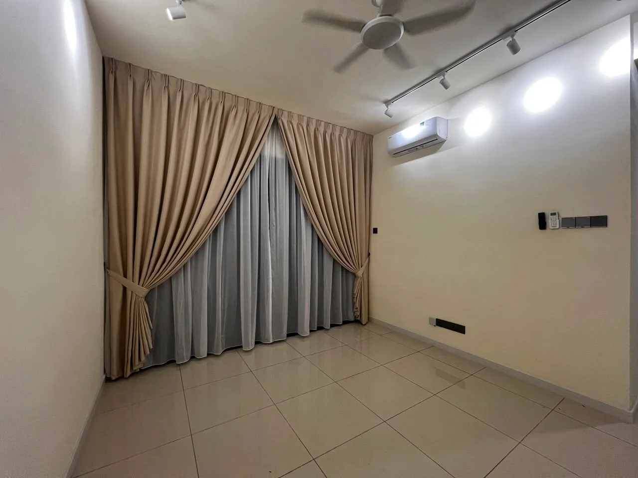 Room features: cream painted walls, white ceiling, recessed downlights, 5-blade ceiling fan, floor-to-ceiling windows with sheer curtains, light grey tiled flooring, wall-mounted air conditioning unit, remote control panel on wall; style: modern.